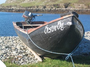 Currach sitting on the barrier of stones diving Lough Bofin from the sea.